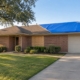 Brick home in Dallas with boarded-up windows and a blue roof tarp after a fire